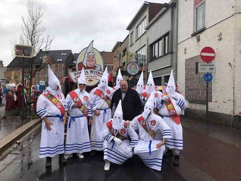 Photo représentant Guy d'Haeslaeer posant avec des participants au carnaval d'Alost déguisés en membres du KKK Jewpop