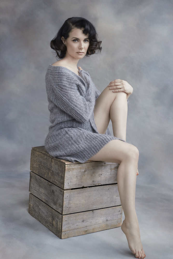 Photo représentant l'actrice Mia Kirshner assise sur une caisse Jewpop